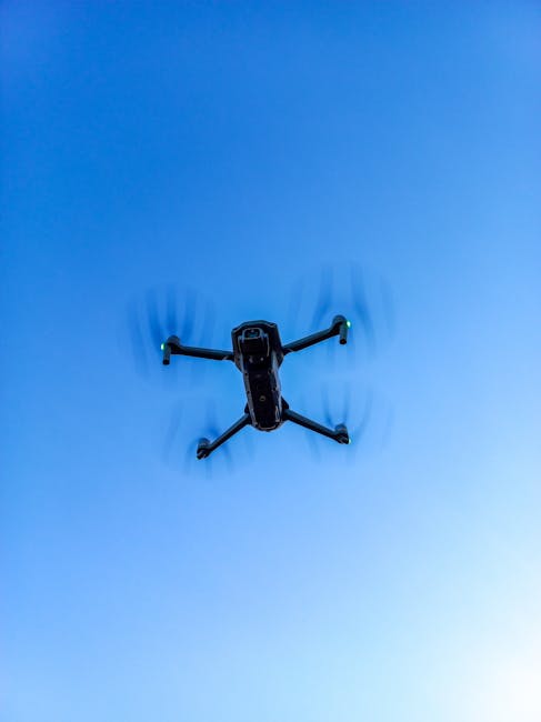 Aerial shot of a drone flying against a clear blue sky, showcasing modern technology.